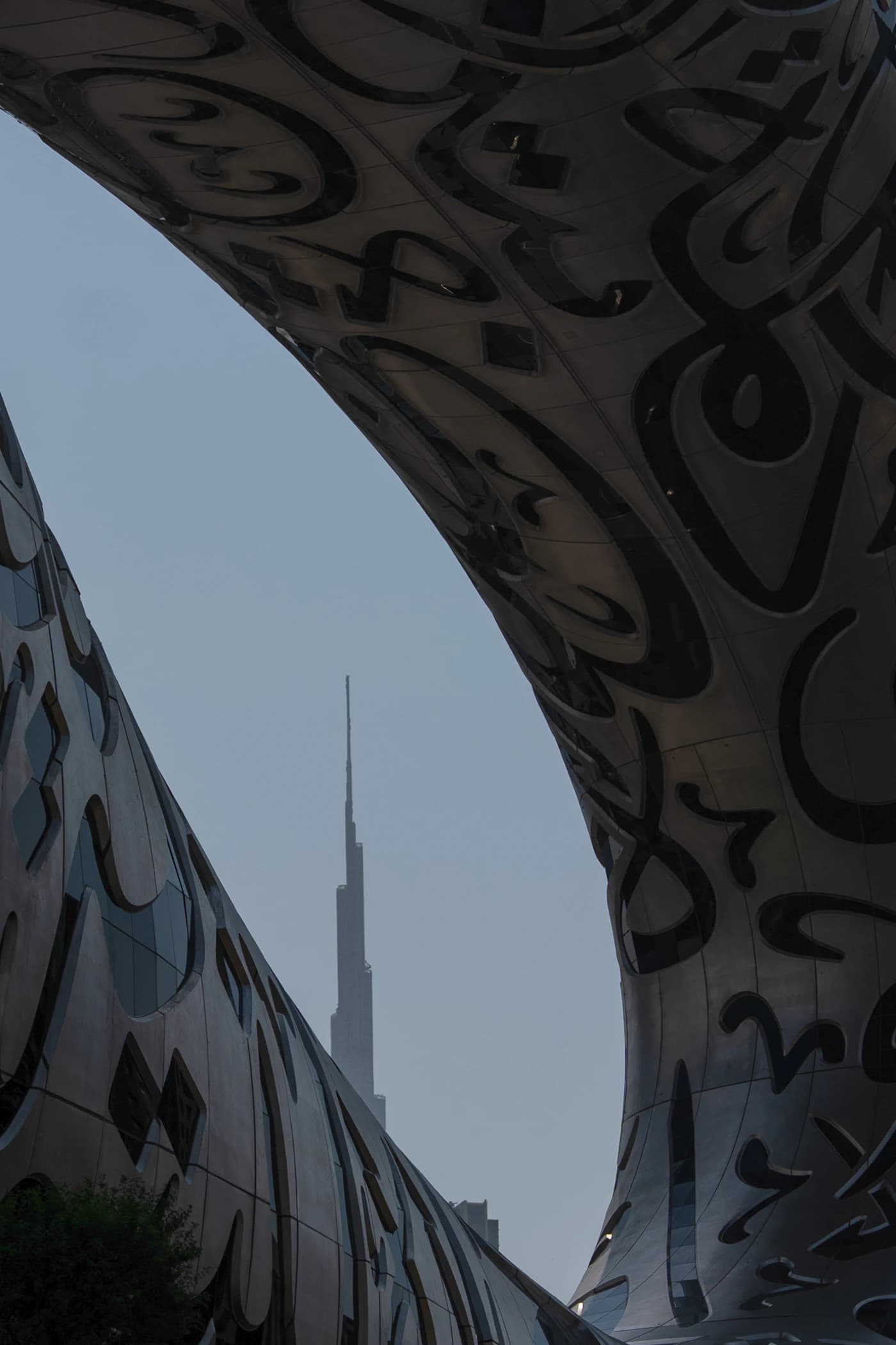 The Burj Khalifa framed through the curved, calligraphy-clad steel facade of Dubai's Museum of the Future.